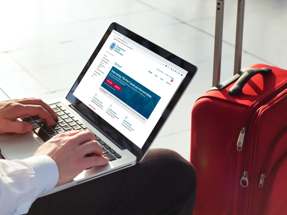 man check TSA Pre website laptop suitcase airport